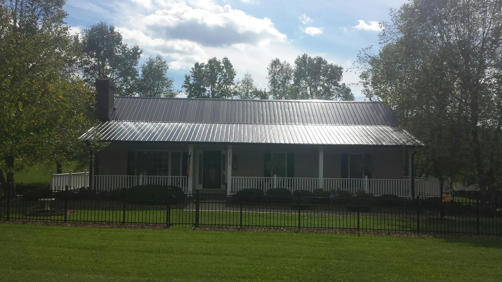 Gray metal roof on a brick ranch with a full width front porch — Gutter Guard Installation work by our crew in Wayne